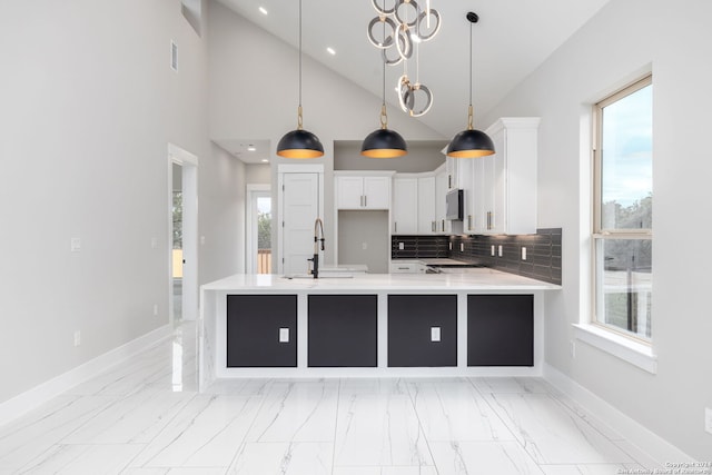 kitchen featuring white cabinets, decorative light fixtures, kitchen peninsula, and backsplash