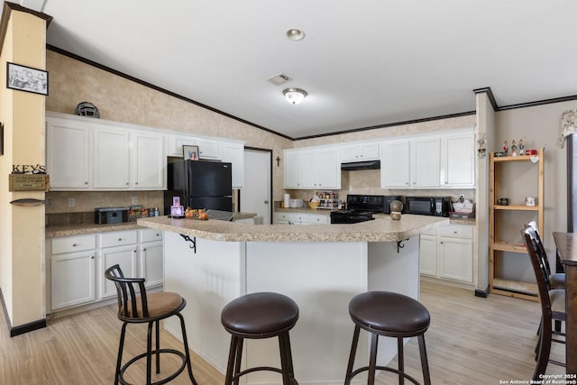 kitchen with a center island, lofted ceiling, black appliances, a kitchen breakfast bar, and white cabinets