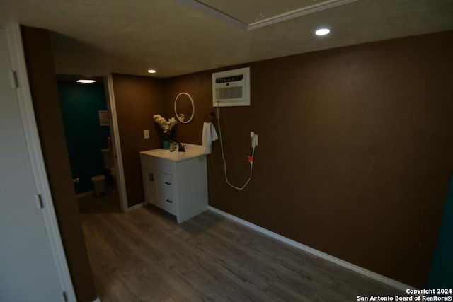 interior space with a wall mounted AC, hardwood / wood-style floors, and sink