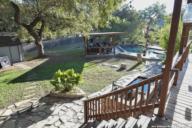 view of yard with a swimming pool side deck, a storage unit, and a patio area