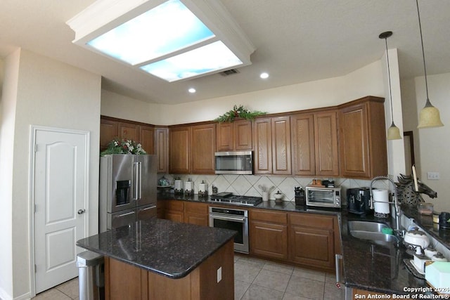 kitchen featuring stainless steel appliances, backsplash, dark stone counters, decorative light fixtures, and light tile patterned floors