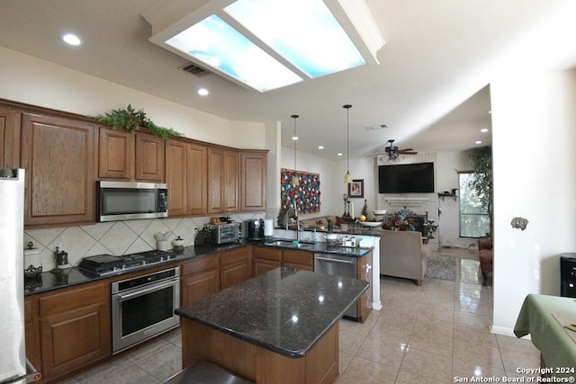 kitchen with ceiling fan, sink, kitchen peninsula, decorative light fixtures, and appliances with stainless steel finishes