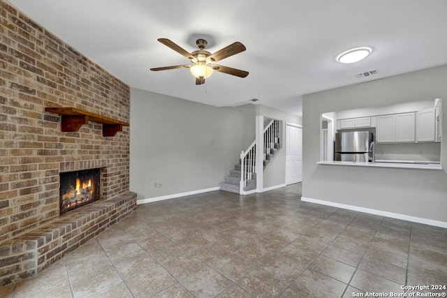 unfurnished living room featuring a brick fireplace and ceiling fan