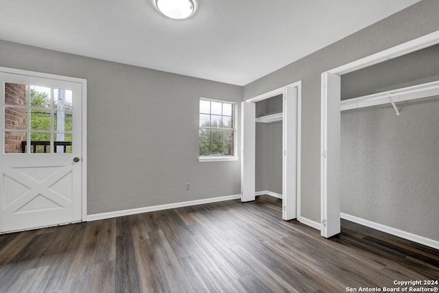 unfurnished bedroom featuring dark wood-type flooring and two closets