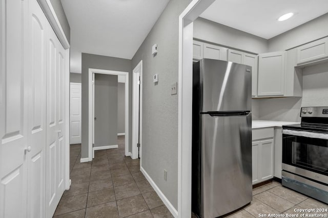 kitchen featuring white cabinets, stainless steel appliances, and light tile patterned flooring