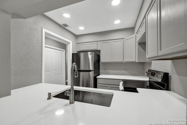 kitchen with gray cabinets, stainless steel fridge, sink, and black electric range oven