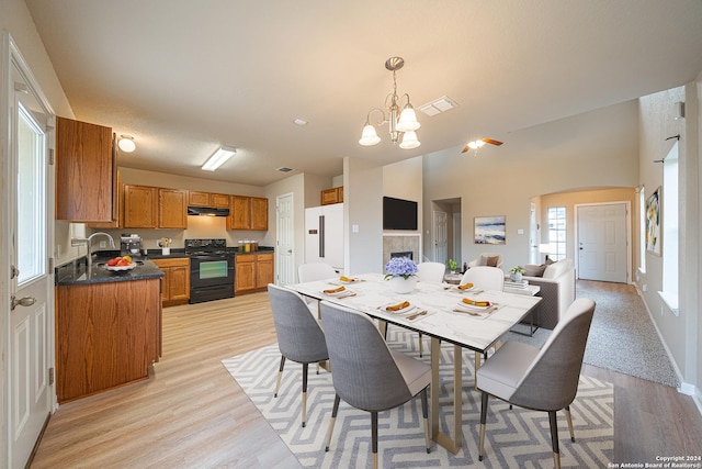 dining area featuring a tile fireplace, sink, light hardwood / wood-style floors, and an inviting chandelier