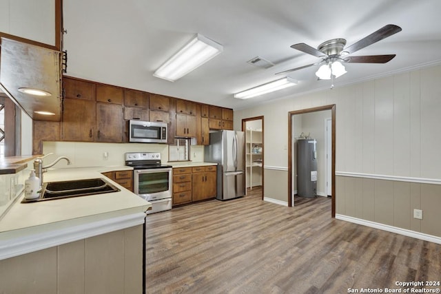 kitchen with appliances with stainless steel finishes, ceiling fan, water heater, sink, and light hardwood / wood-style floors