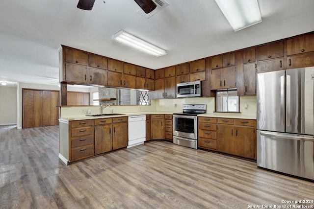 kitchen with appliances with stainless steel finishes, light hardwood / wood-style flooring, ceiling fan, and sink