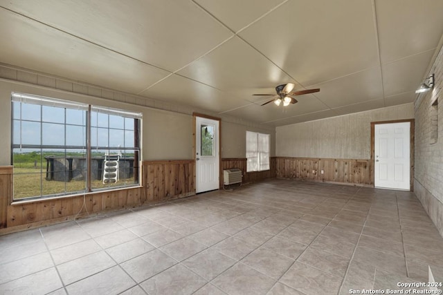 tiled empty room with ceiling fan and wood walls