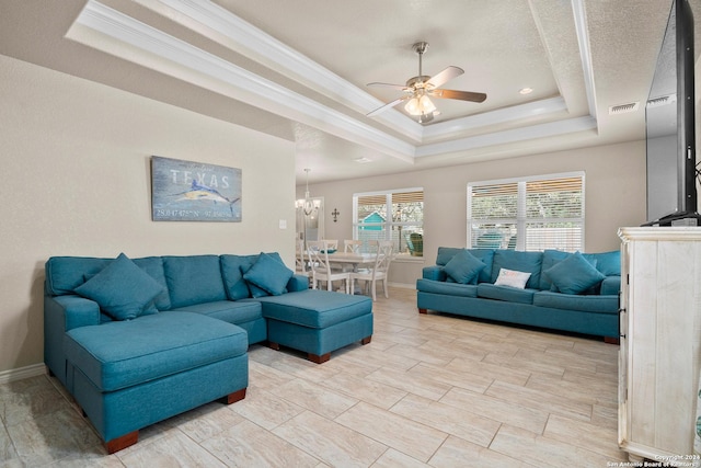 living room featuring a tray ceiling, ceiling fan with notable chandelier, and ornamental molding