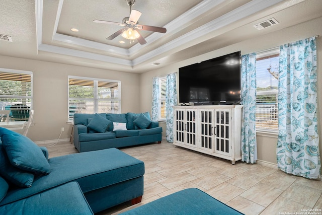 living room with a raised ceiling, ceiling fan, crown molding, and a textured ceiling