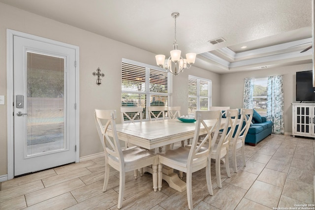 dining area featuring a tray ceiling, crown molding, a textured ceiling, and a notable chandelier