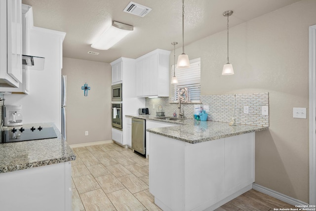 kitchen with white cabinetry, sink, light stone counters, decorative light fixtures, and appliances with stainless steel finishes