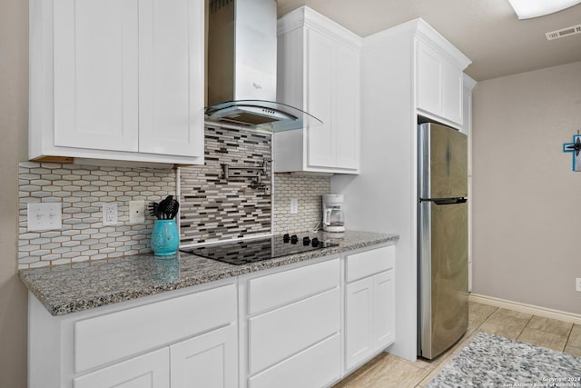 kitchen featuring stainless steel refrigerator, white cabinetry, and wall chimney exhaust hood