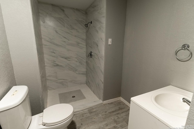 bathroom featuring tiled shower, vanity, hardwood / wood-style flooring, and toilet