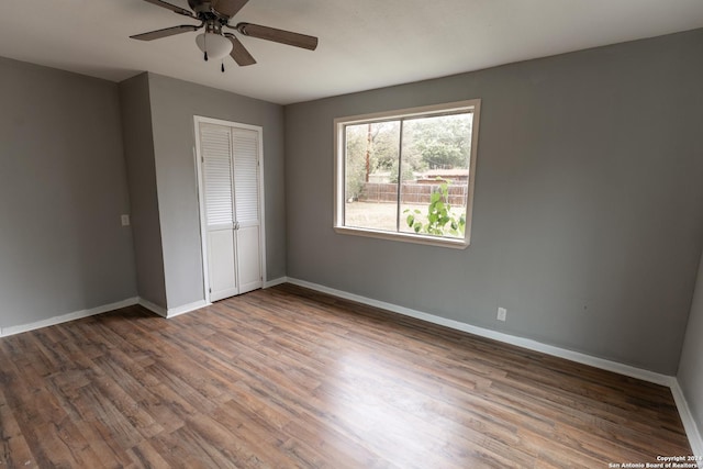 unfurnished bedroom with a closet, dark hardwood / wood-style floors, and ceiling fan