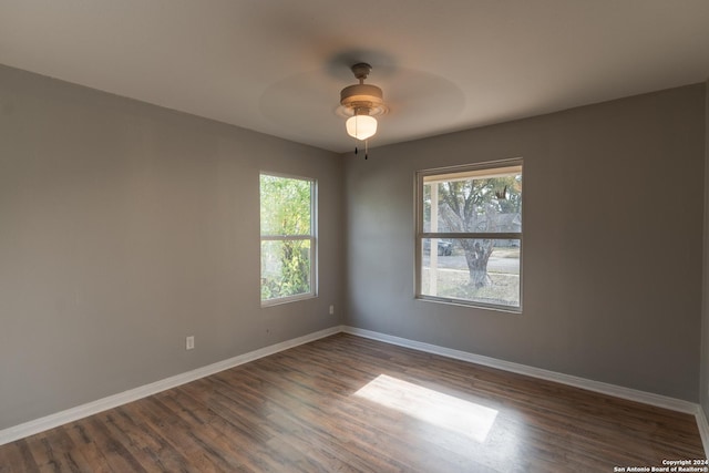 empty room with plenty of natural light, ceiling fan, and dark wood-type flooring