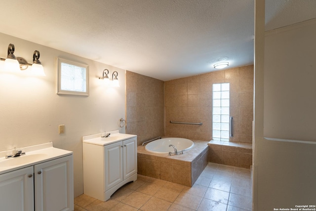 bathroom featuring a textured ceiling, vanity, a relaxing tiled tub, and tile patterned floors