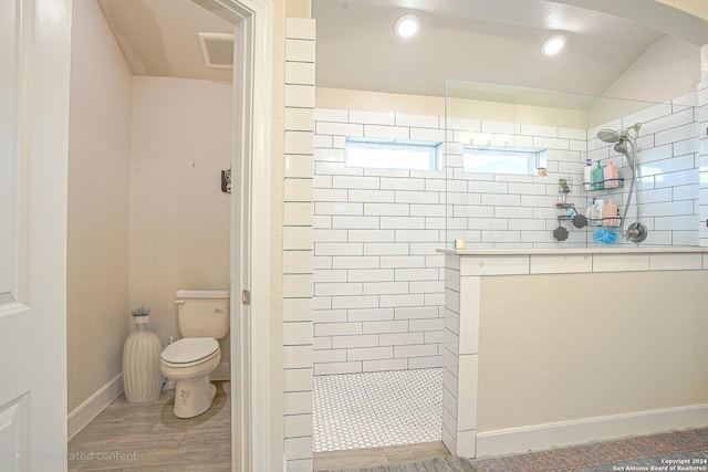 bathroom with hardwood / wood-style floors, toilet, and tiled shower