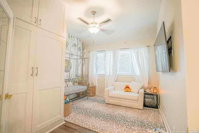 bedroom featuring hardwood / wood-style flooring, ceiling fan, and a crib