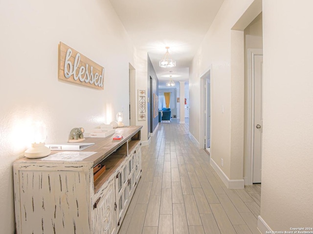 hallway with a chandelier and light hardwood / wood-style floors