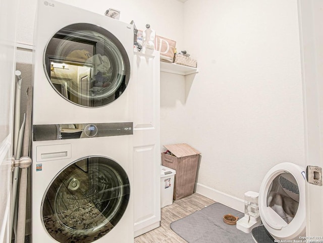 clothes washing area featuring stacked washing maching and dryer and light hardwood / wood-style floors