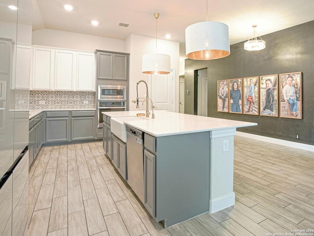 kitchen featuring sink, light hardwood / wood-style flooring, decorative backsplash, decorative light fixtures, and stainless steel appliances