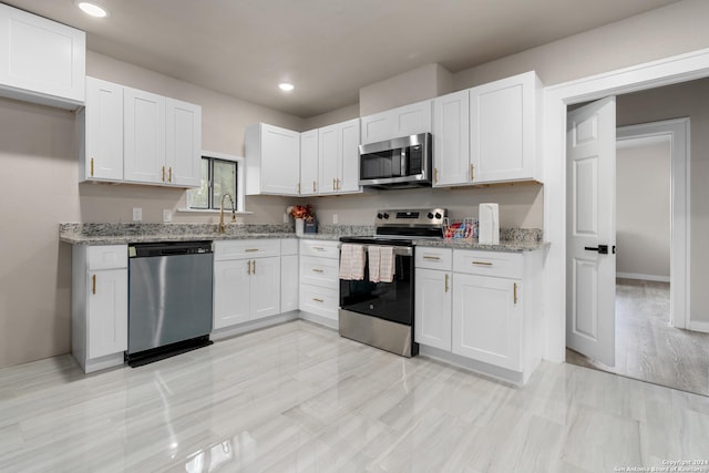 kitchen with white cabinetry, light hardwood / wood-style flooring, light stone countertops, and appliances with stainless steel finishes