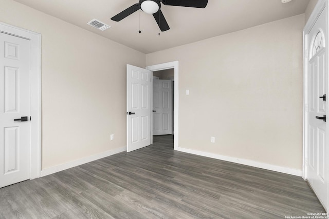 unfurnished bedroom with ceiling fan and dark wood-type flooring