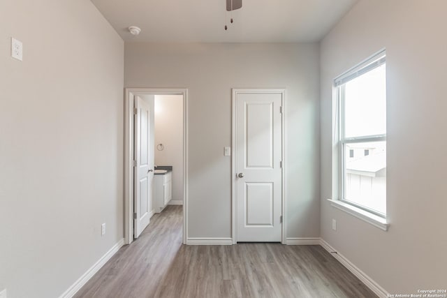 unfurnished bedroom with ceiling fan, ensuite bath, light hardwood / wood-style flooring, and multiple windows