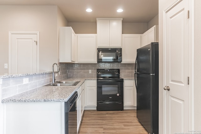 kitchen featuring white cabinetry, sink, tasteful backsplash, black appliances, and light wood-type flooring