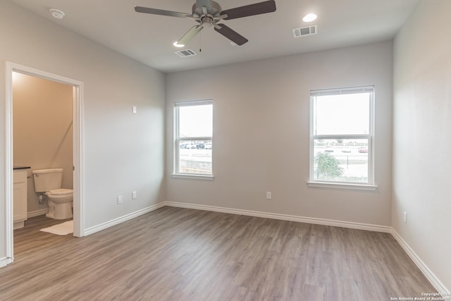 unfurnished bedroom featuring ceiling fan, light hardwood / wood-style flooring, connected bathroom, and multiple windows