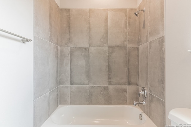 bathroom with tiled shower / bath combo and toilet