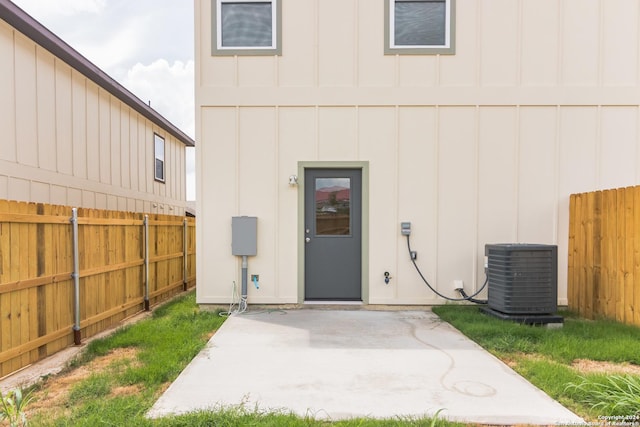 view of exterior entry featuring central air condition unit and a patio