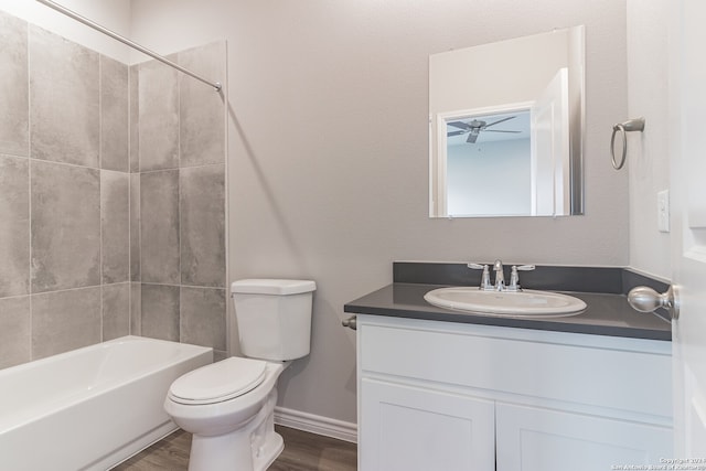 full bathroom with hardwood / wood-style floors, vanity, ceiling fan, tiled shower / bath combo, and toilet