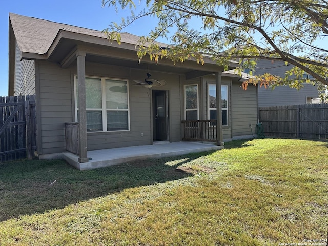 back of property with a yard and ceiling fan