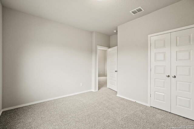 unfurnished bedroom with light carpet and a closet