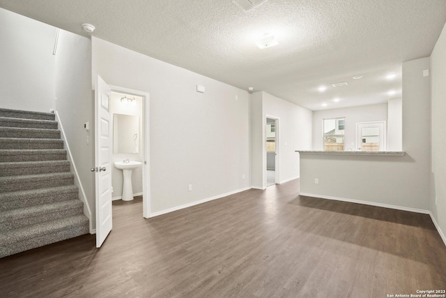 unfurnished living room with a textured ceiling, sink, and dark hardwood / wood-style floors