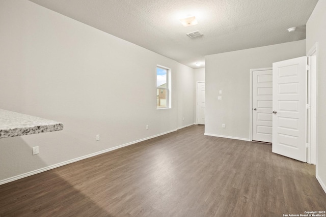 unfurnished bedroom with a textured ceiling and dark wood-type flooring