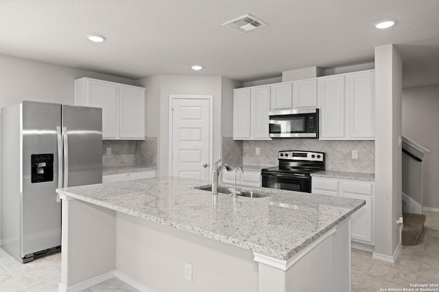 kitchen with sink, a kitchen island with sink, stainless steel appliances, decorative backsplash, and white cabinets