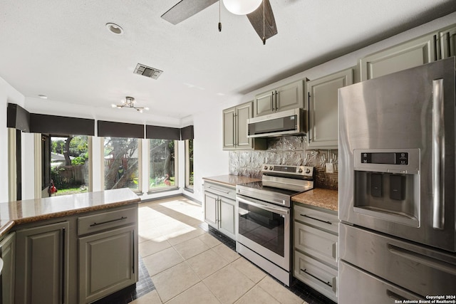 kitchen featuring decorative backsplash, appliances with stainless steel finishes, gray cabinets, and light tile patterned flooring