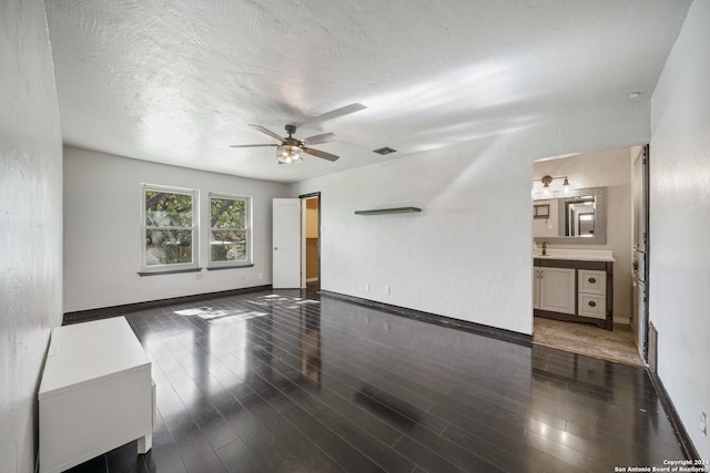 unfurnished living room with a textured ceiling, dark hardwood / wood-style floors, ceiling fan, and sink