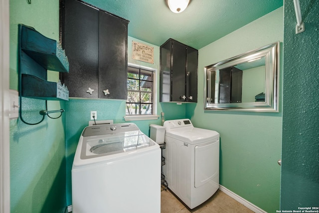 laundry room featuring washer and dryer, light tile patterned floors, cabinets, and a textured ceiling