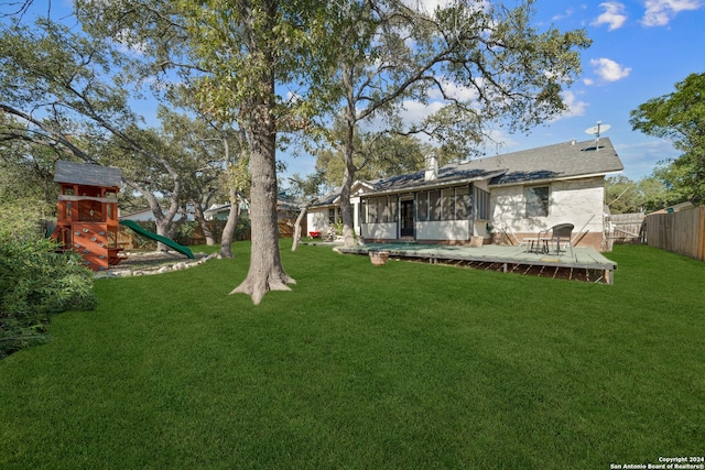 view of yard with a playground, a deck, and a sunroom