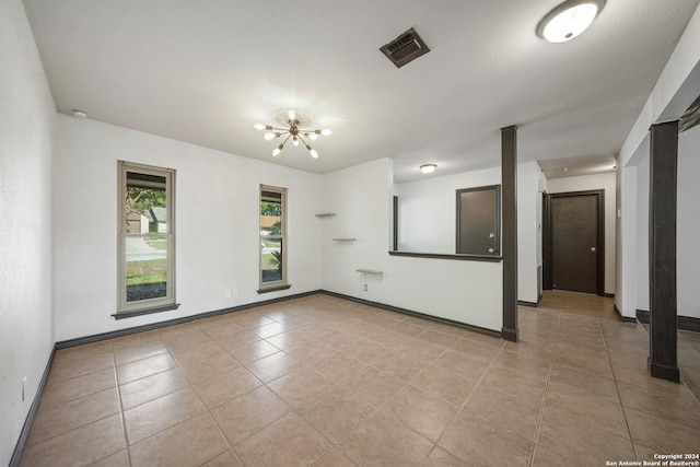 empty room with light tile patterned floors and an inviting chandelier