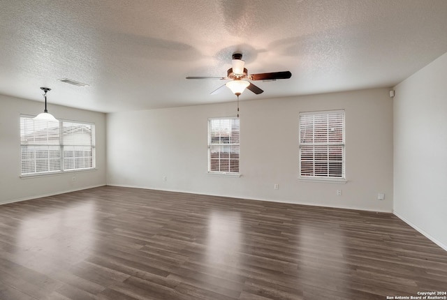 empty room featuring a textured ceiling, dark hardwood / wood-style flooring, plenty of natural light, and ceiling fan