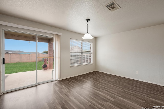 unfurnished dining area with a textured ceiling and dark hardwood / wood-style flooring