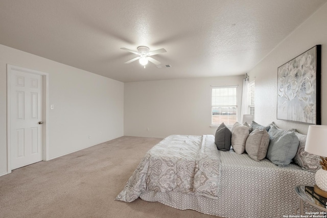 carpeted bedroom with ceiling fan and a textured ceiling