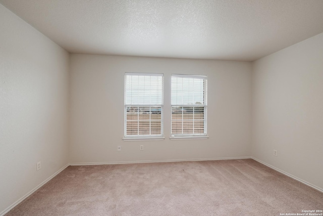 carpeted empty room featuring a textured ceiling